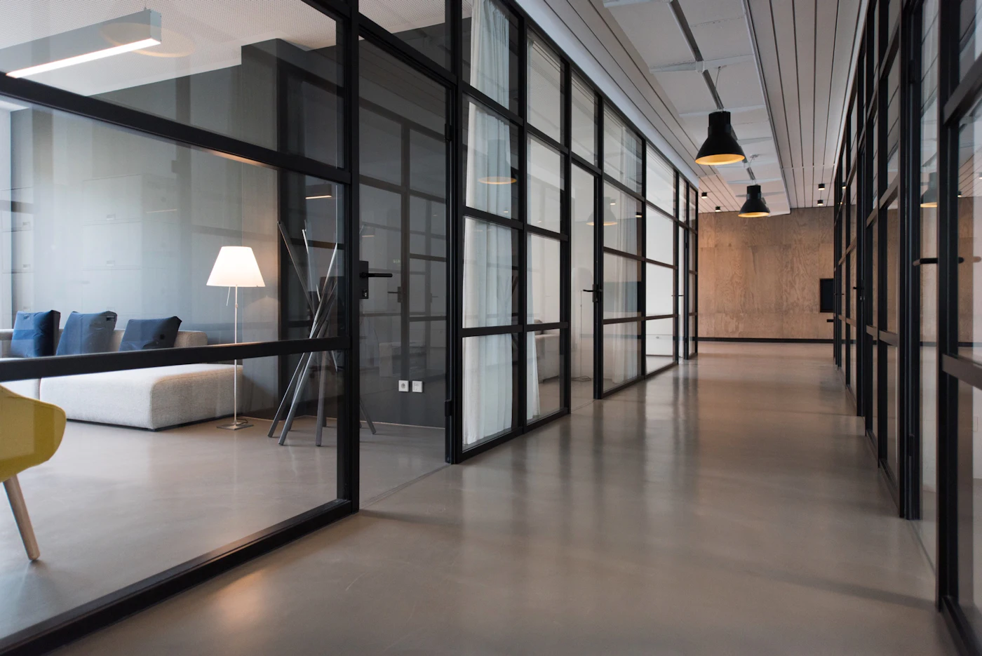 A long glazed corridor with dark steel frames and soft daylight