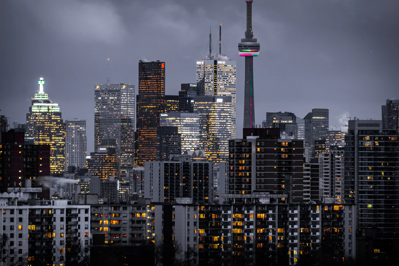 The Toronto skyline at dusk, the CN Tower rising above lit residential towers